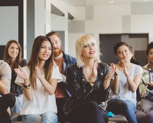 Large group of happy multi ethnic students attending a seminar at the university, clapping hands.
