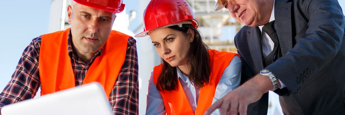 three construction professionals reviewing blueprints