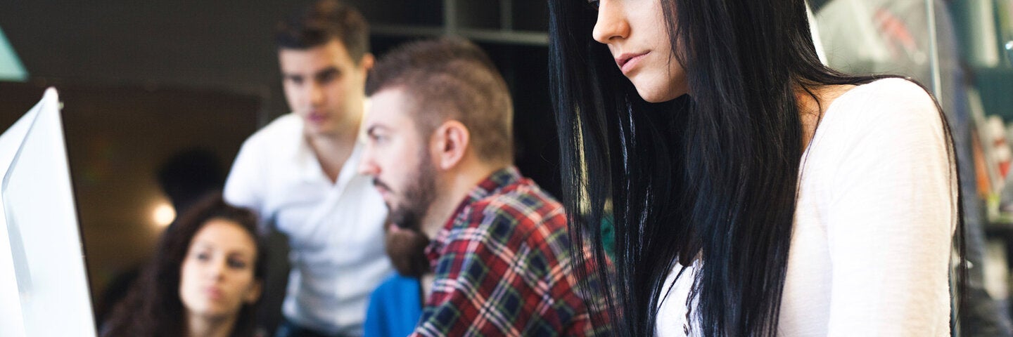 Female design student working on laptop in classroom.