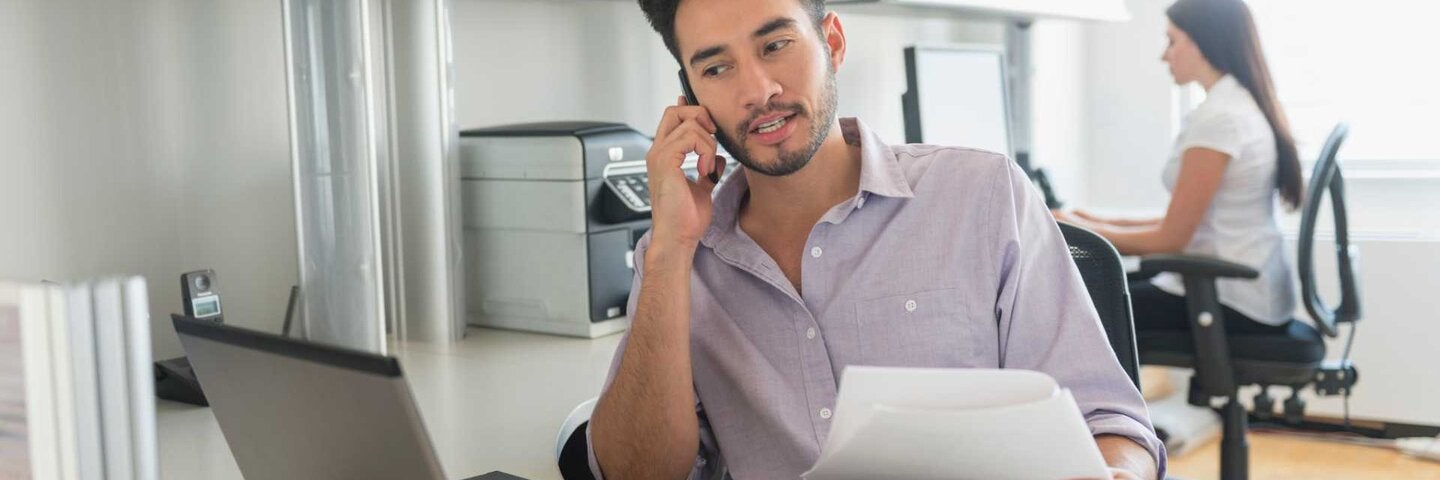 Male executive assistant taking a call in the office.
