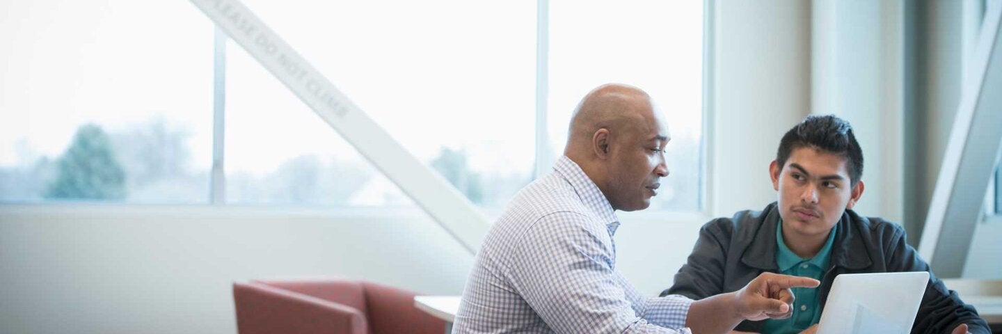 Mentor helping student use laptop
