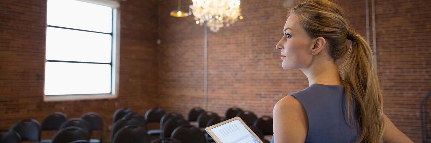 Ambitious businesswoman with digital tablet in conference room with chandelier