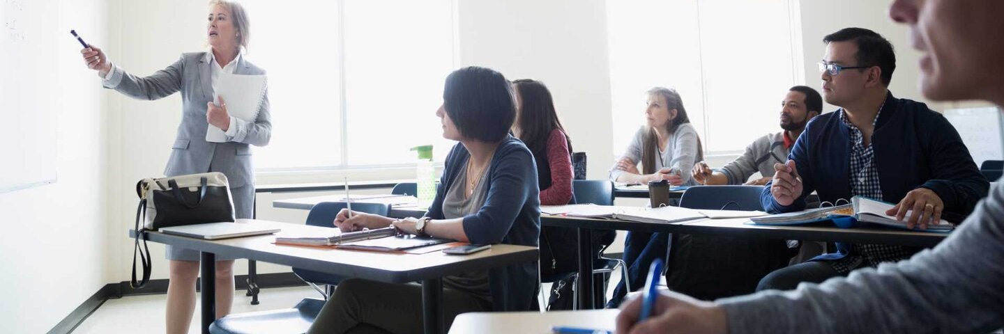 Instructor at whiteboard teaching adult education students in classroom