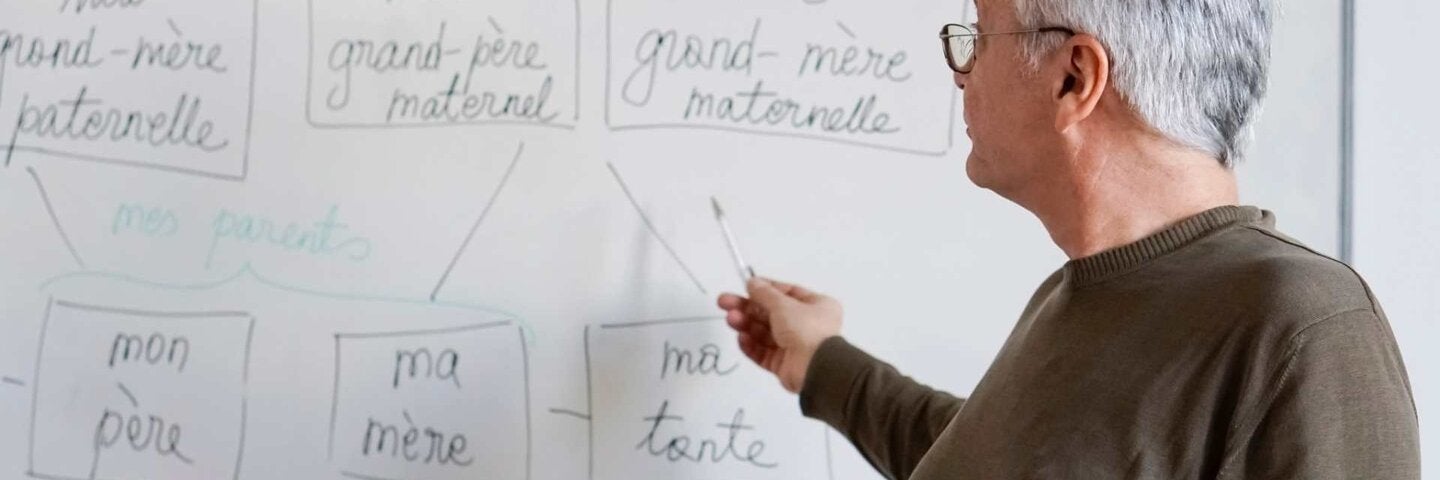 Instructor writing french words on a whiteboard in the classroom.