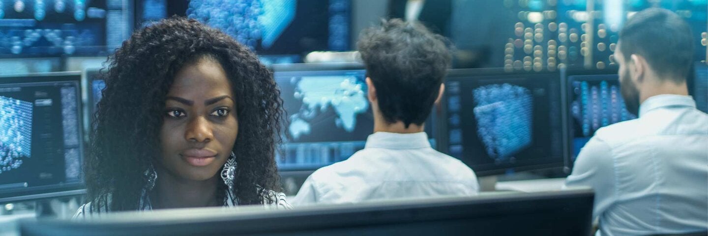 Female Computer Engineer Works on a Neural Network/ Artificial Intelligence Project with Her Multi-Ethnic Team of Specialist. Office Has Multiple Screens Showing 3D Visualization.