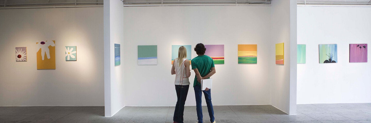 woman and man with notebook looking at art in a gallery
