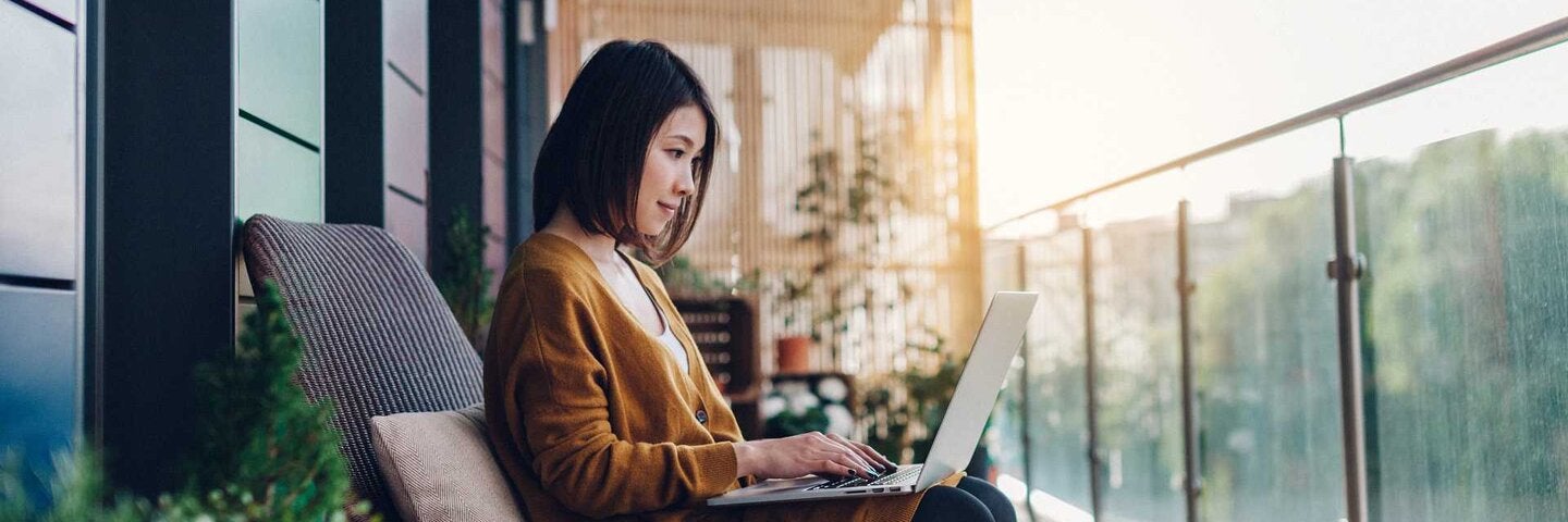 Young woman working on laptop on a balcony