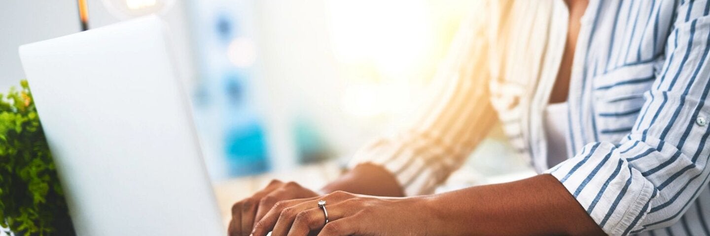 Woman typing memoir on laptop at home