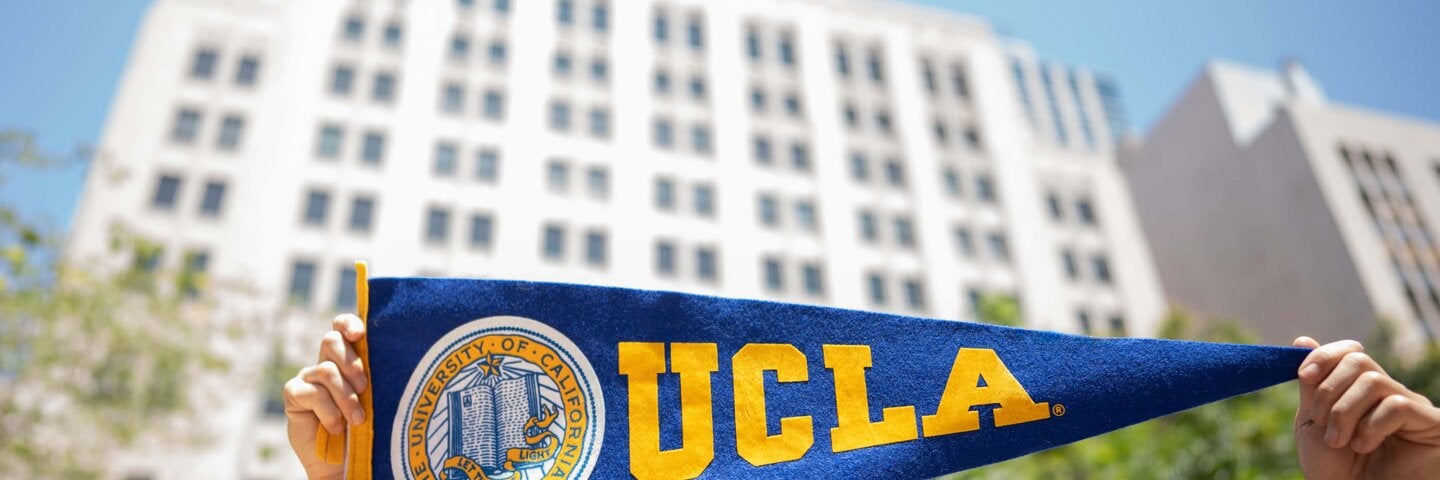 UCLA's downtown Los Angeles Trust building, with hands holding a pennant in foreground