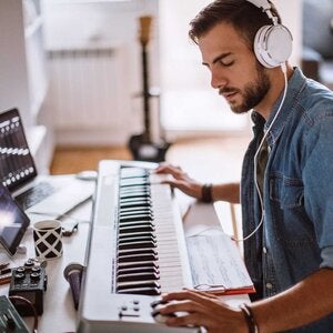 individual wearing headphones using an electronic piano