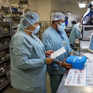 Two medical professionals in protective gear handling medical package